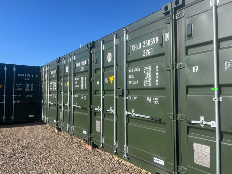 Row of green shipping containers against a clear blue sky at Rome Street Depot