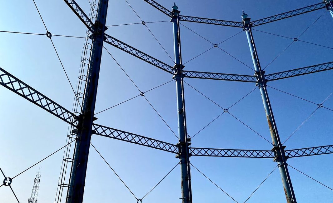 Metal former gasholder against a clear blue sky, illustrating industrial architecture at Rome Street Depot