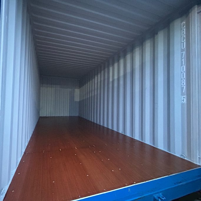 Empty 20 foot shipping container interior with metal walls and wooden floor.