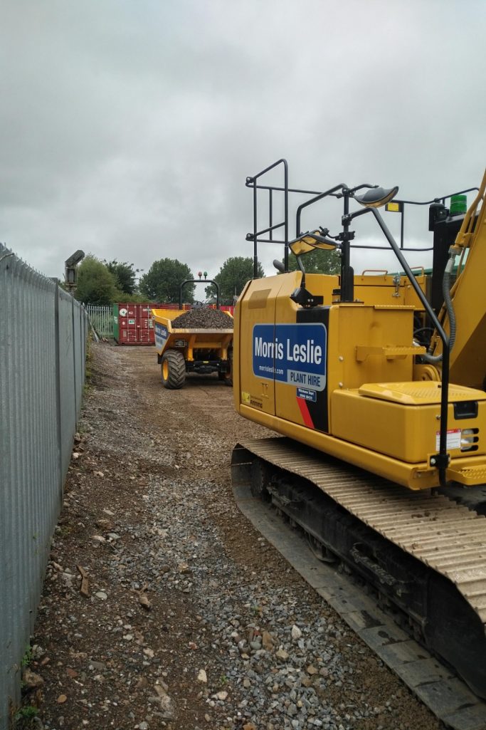 Construction site with heavy machinery, including a yellow excavator and dumper truck.
